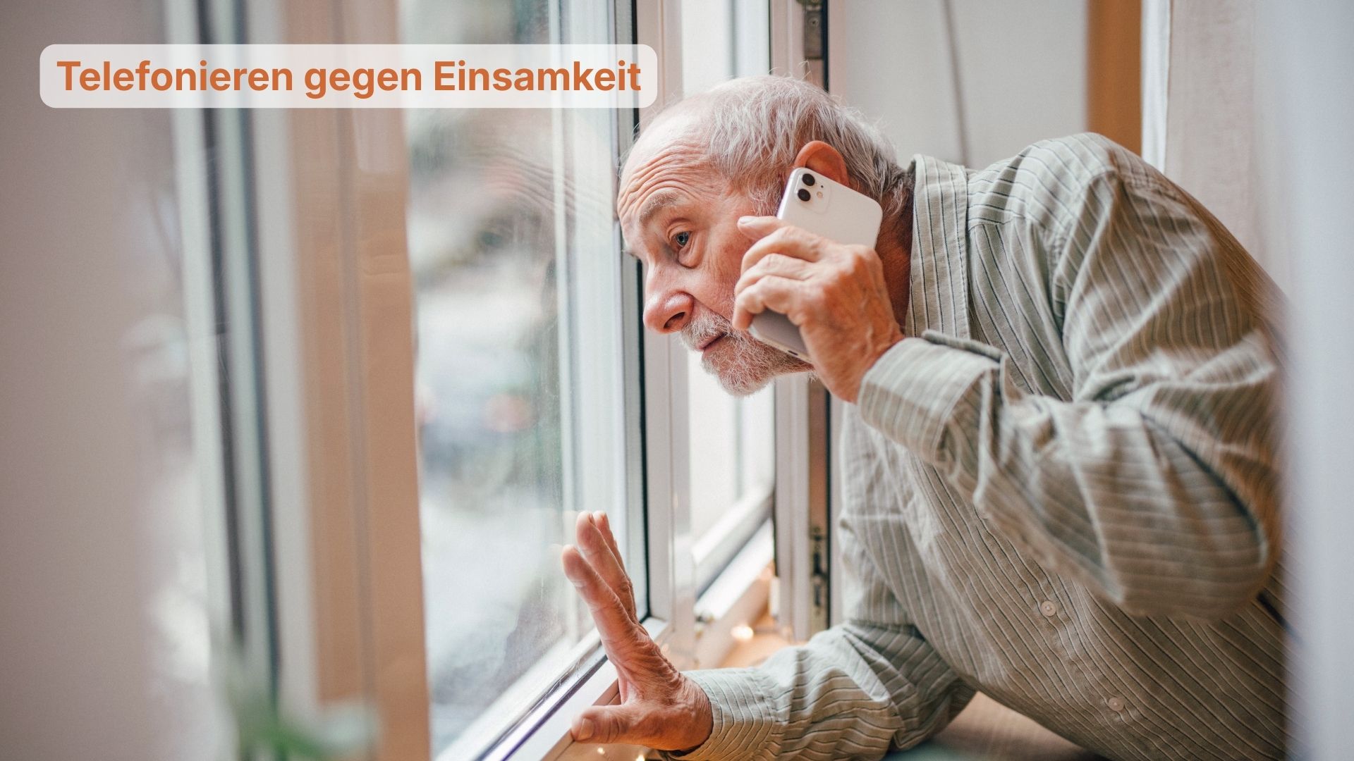 Eine Person steht am geöffneten Fenster und telefoniert, während sie mit der freien Hand gegen die Fensterscheibe lehnt. Links im Bild steht der Text: „Telefonieren gegen Einsamkeit